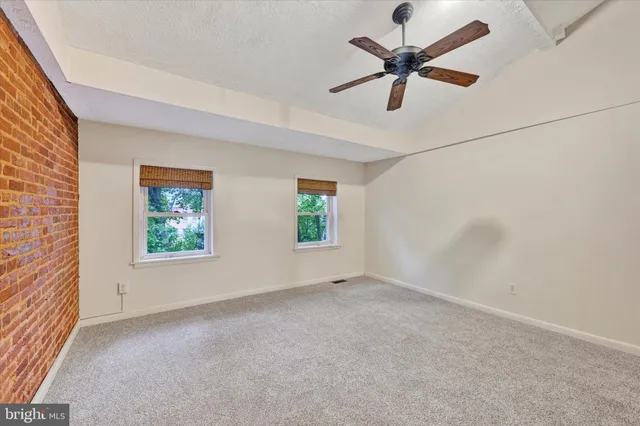 an empty room with windows and ceiling fan