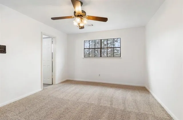 an empty room with a chandelier fan and windows