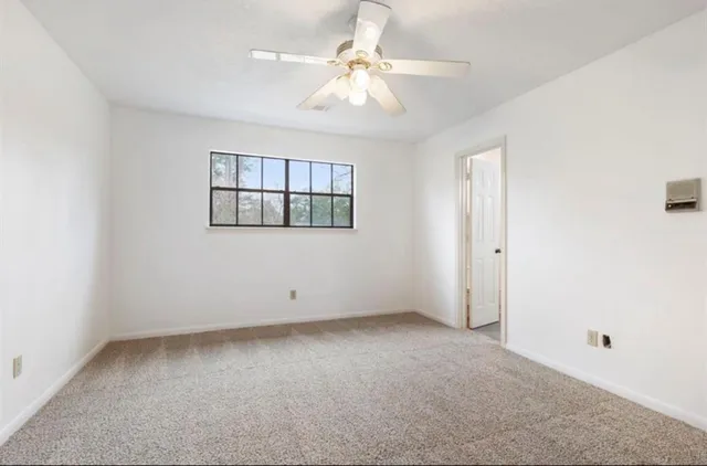 an empty room with a kitchen and a ceiling fan