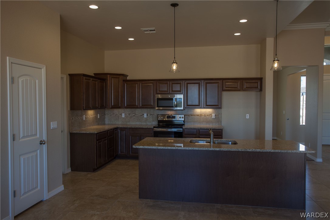 4861 North Neal Ranch Road Kingman, AZ 86401 - Photo 16 of 36 a kitchen with kitchen island granite countertop a stove and a sink