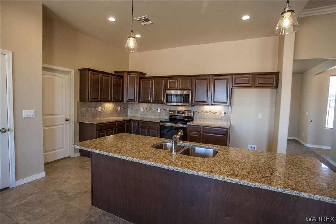 4861 North Neal Ranch Road Kingman, AZ 86401 - Photo 17 of 36 a kitchen with kitchen island granite countertop a sink a refrigerator and a stove