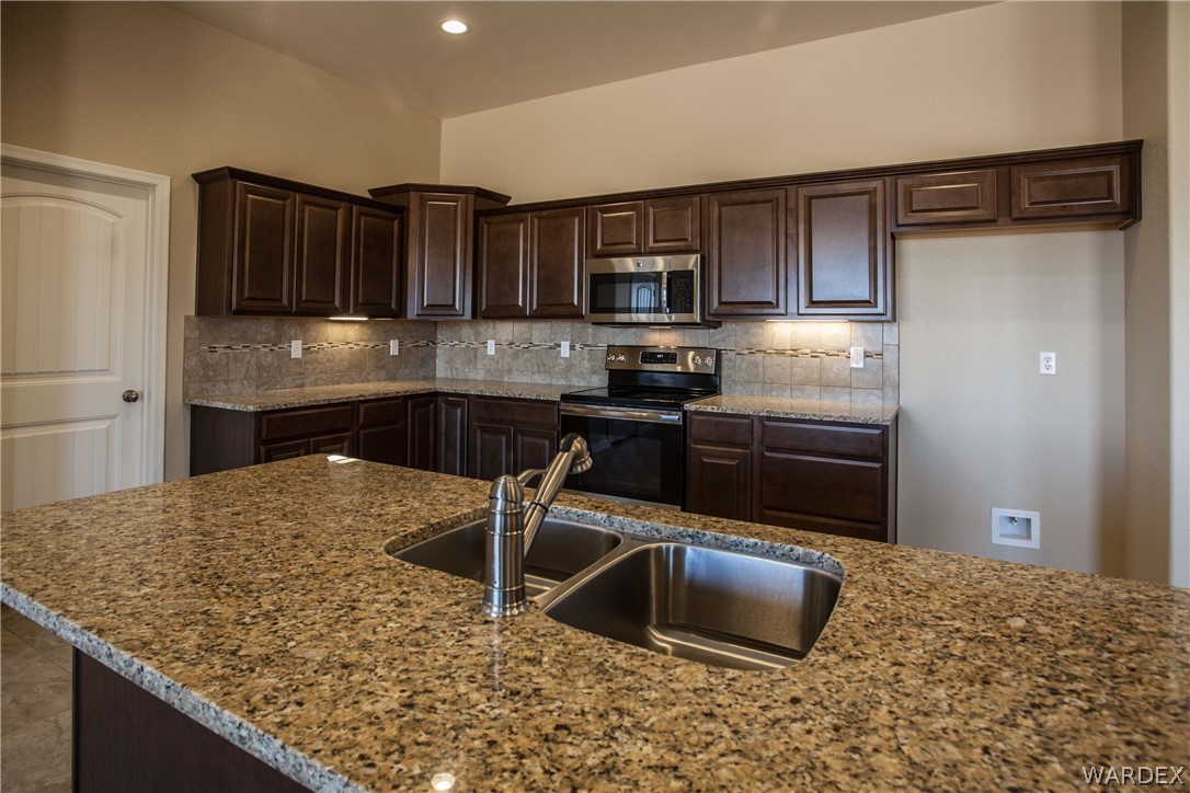4861 North Neal Ranch Road Kingman, AZ 86401 - Photo 18 of 36 a kitchen with stainless steel appliances granite countertop a sink stove and refrigerator