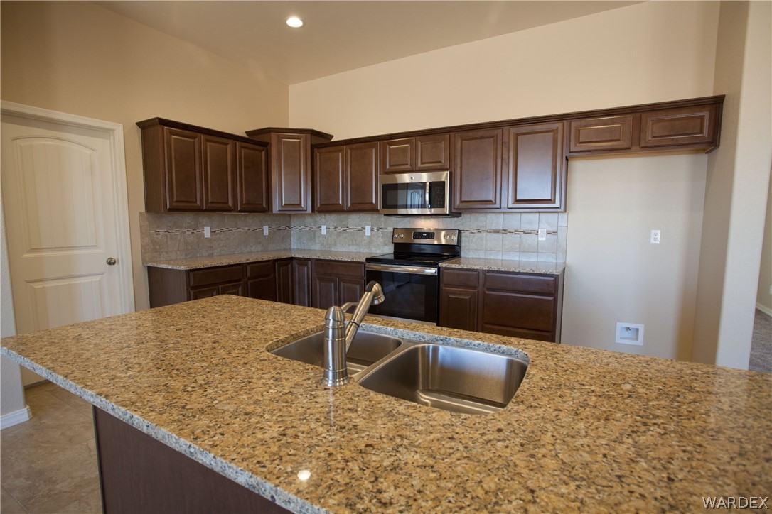 4861 North Neal Ranch Road Kingman, AZ 86401 - Photo 19 of 36 a kitchen with stainless steel appliances granite countertop a sink stove and refrigerator