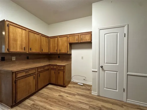 an empty room with wooden floor chandelier fan and windows