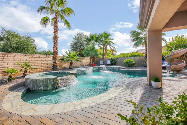 a view of a swimming pool with a lawn chairs under an umbrella