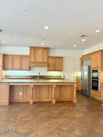 a large kitchen with stainless steel appliances a large counter top and a refrigerator