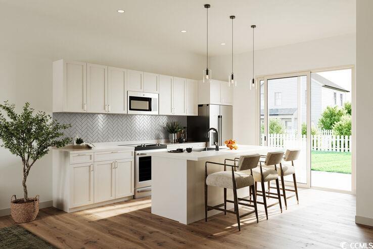 8840 Henry Road, Unit DEWBERRY Longs, SC 29568 - Photo 5 of 29 Kitchen with white cabinets, dark hardwood / wood-style flooring, white appliances, and a kitchen island with sink