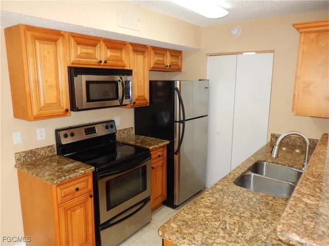 a kitchen with granite countertop a refrigerator stove and microwave