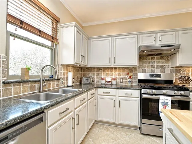 a kitchen with white cabinets sink and appliances