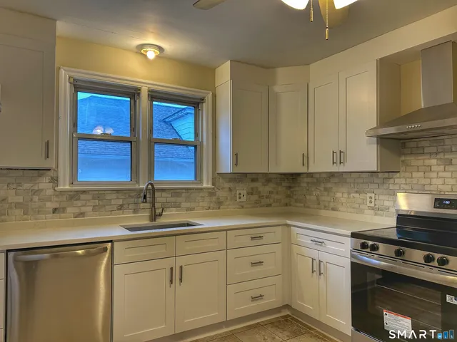 a kitchen with granite countertop a sink stainless steel appliances and cabinets