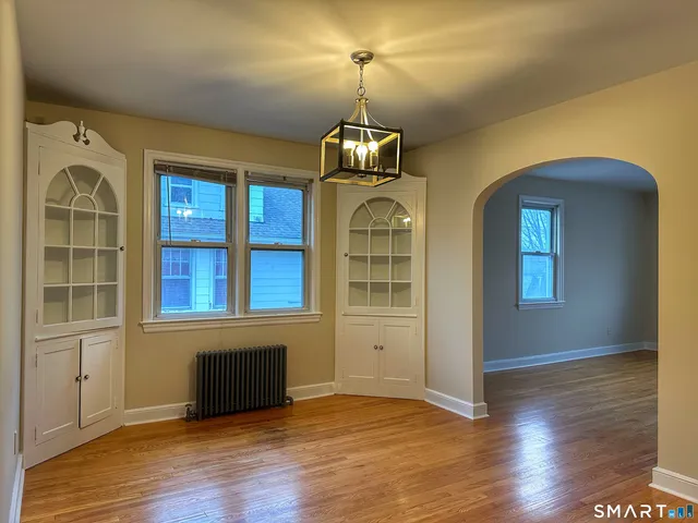 an empty room with wooden floor cabinet and windows