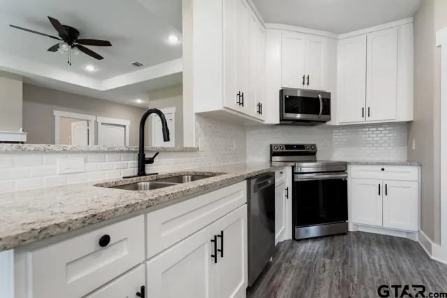 a kitchen with granite countertop a sink stainless steel appliances and cabinets