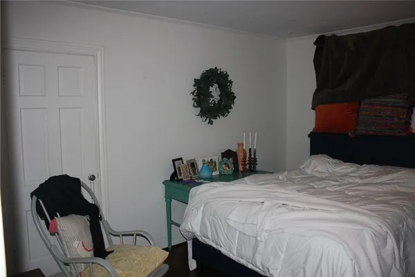 a bedroom with a bed a dresser and a painting