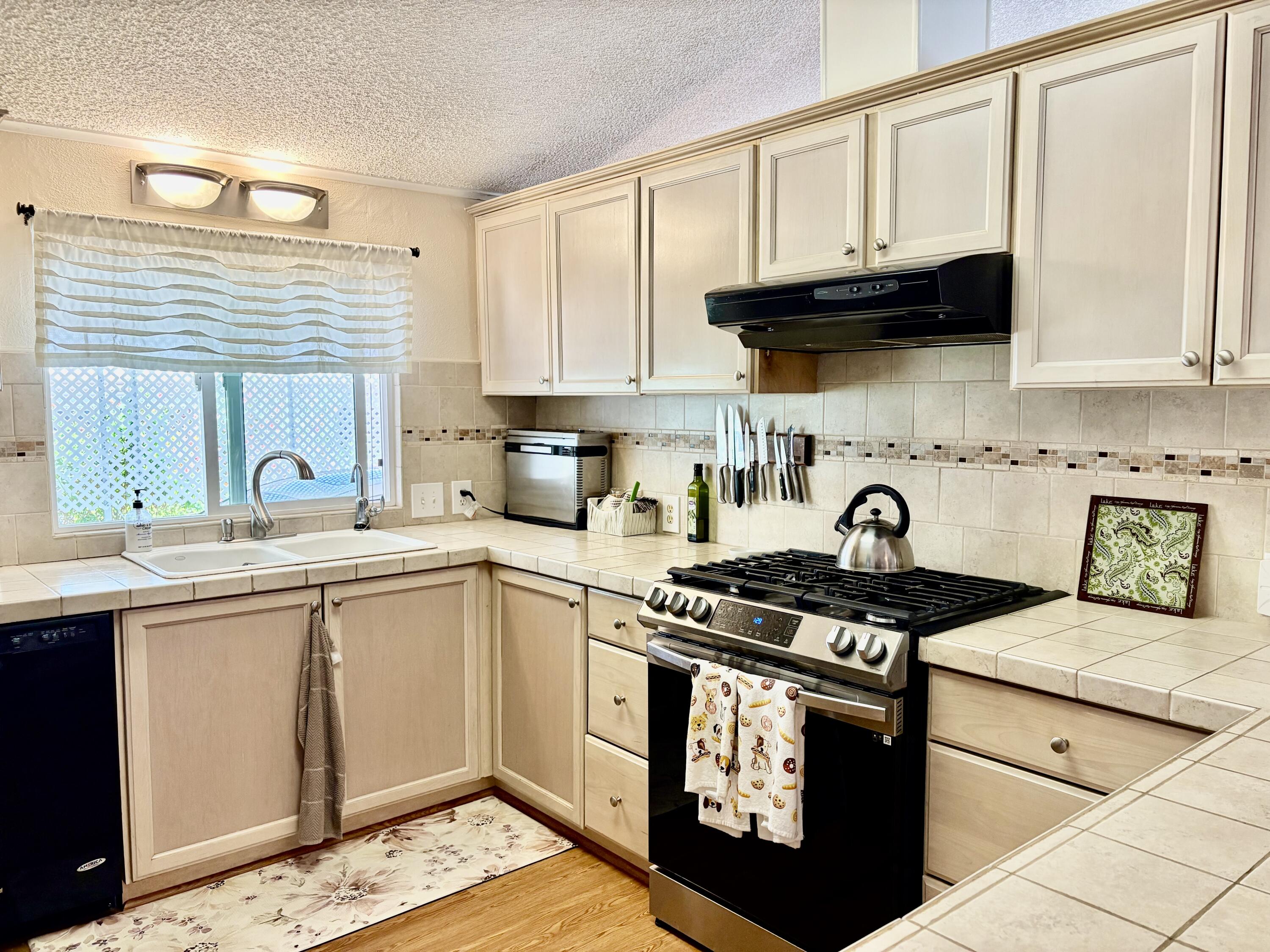 74711 Dillon Road, Unit 635 Desert Hot Springs, CA 92241 - Photo 8 of 55 a kitchen with stainless steel appliances granite countertop a stove a sink and a microwave