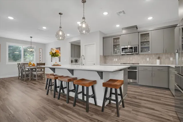 a kitchen with stainless steel appliances kitchen island granite countertop a dining table chairs and sink