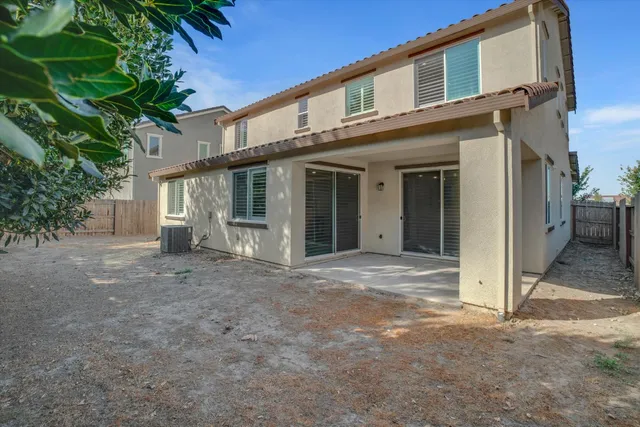 a view of a house with a yard and large tree