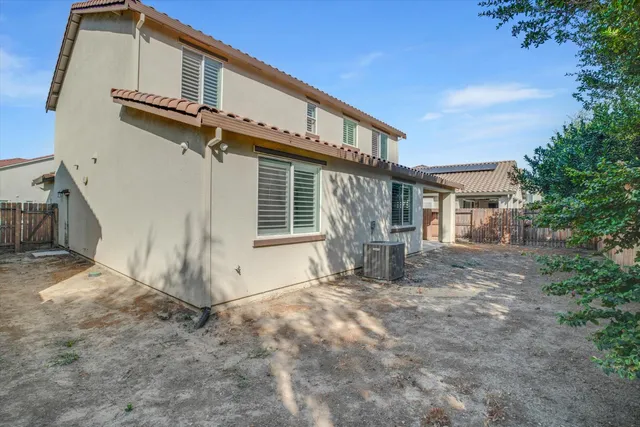 a front view of a house with large tree and wooden fence