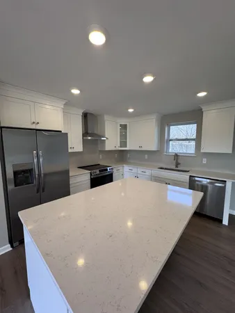 a large kitchen with kitchen island a stove a sink a refrigerator and cabinets