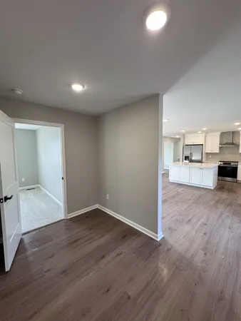 an empty room with wooden floor and a kitchen
