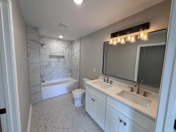 a bathroom with a bathtub shower sink vanity and toilet