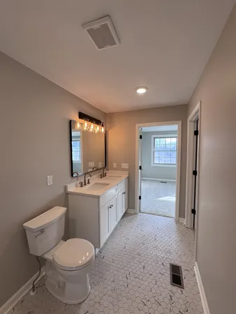a bathroom with a granite countertop toilet sink and mirror
