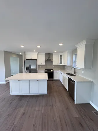 a large kitchen with stainless steel appliances kitchen island a large counter top and a stove top oven