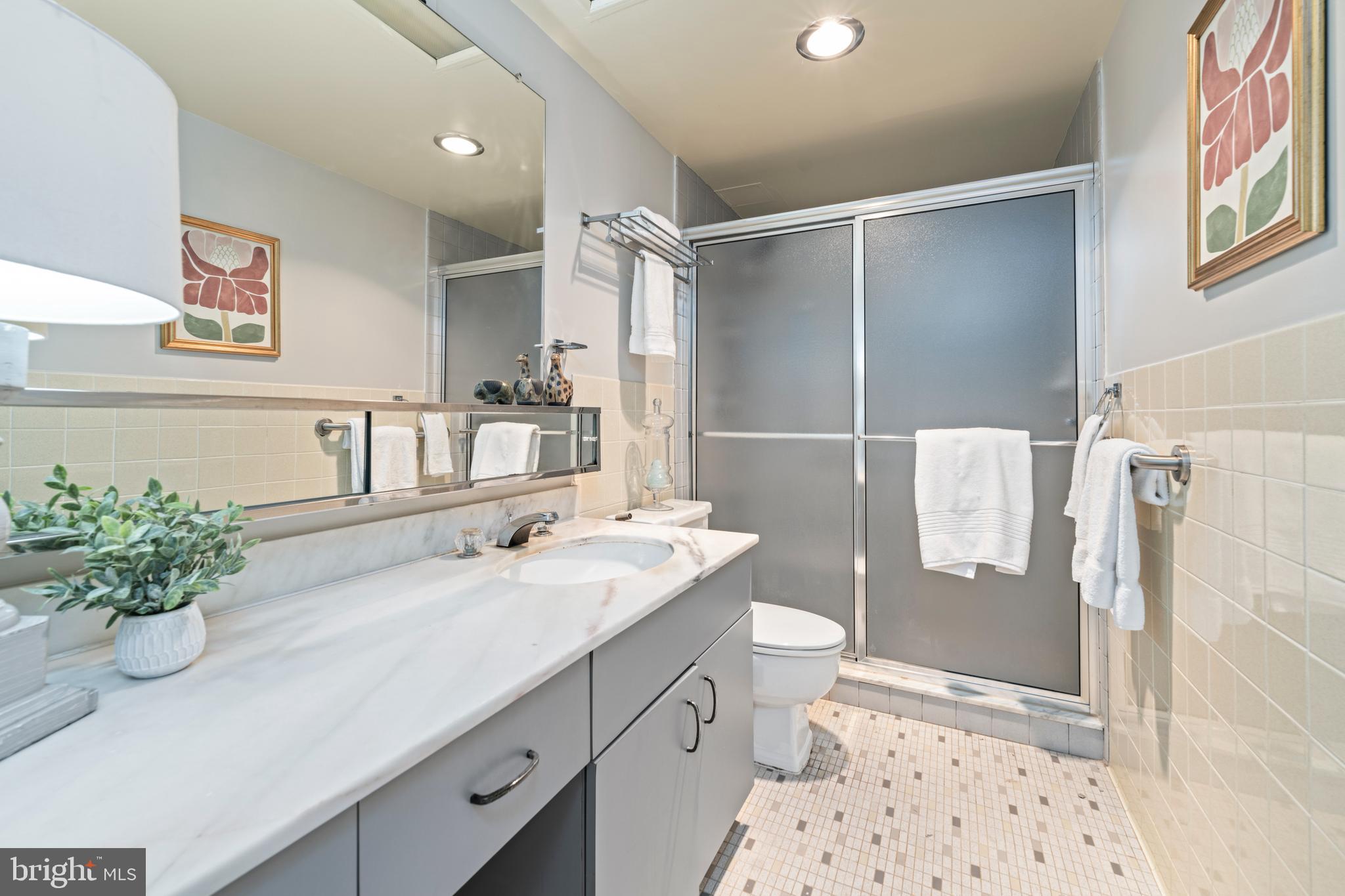 4401 Roland Avenue, Unit 115 Baltimore, MD 21210 - Photo 35 of 54 a bathroom with a double vanity sink mirror and shower