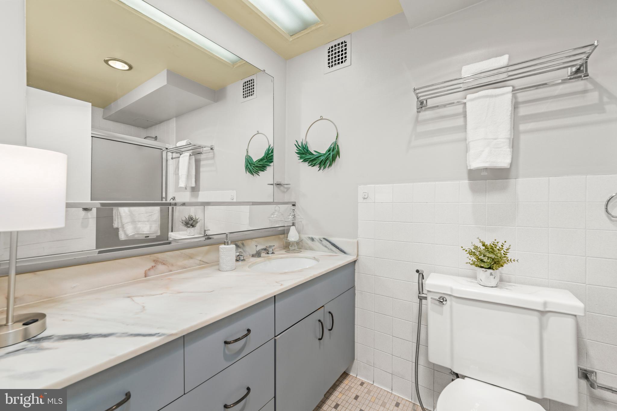 4401 Roland Avenue, Unit 115 Baltimore, MD 21210 - Photo 42 of 54 a bathroom with a granite countertop sink a mirror and a shower