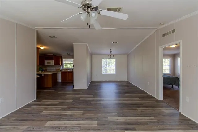 a view of a hallway with wooden floor and a kitchen