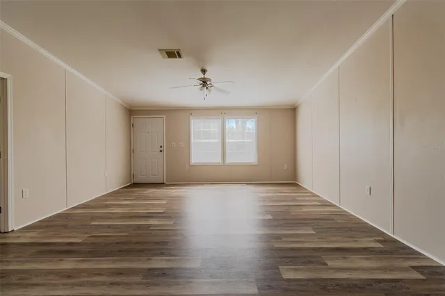 a view of an empty room with window and wooden floor