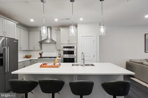 a kitchen with stainless steel appliances a dining table chairs sink and cabinets