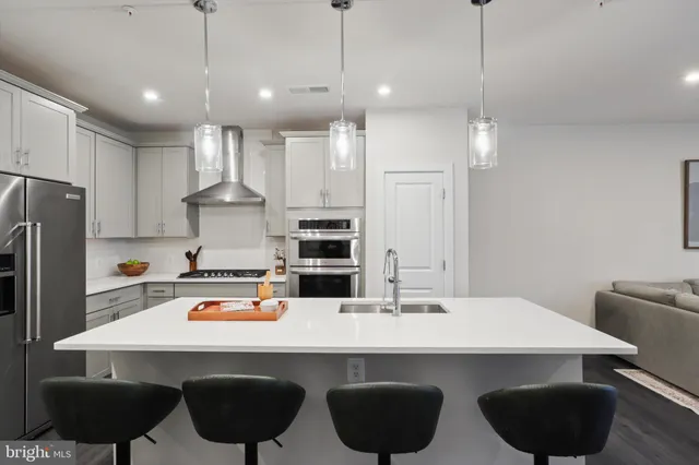 a kitchen with stainless steel appliances a dining table chairs sink and cabinets