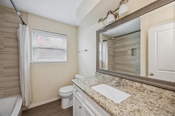 a bathroom with a granite countertop toilet a sink and mirror