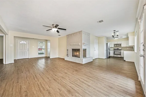 a view of a livingroom with a fireplace a ceiling fan and wooden floor