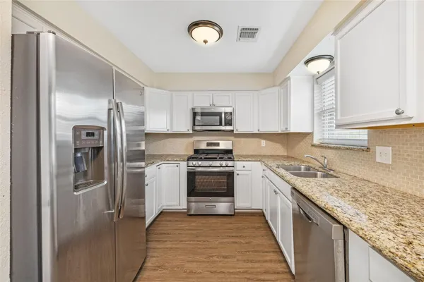 a kitchen with granite countertop a refrigerator stove and sink