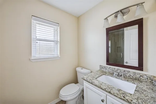 a bathroom with a granite countertop toilet a sink and mirror