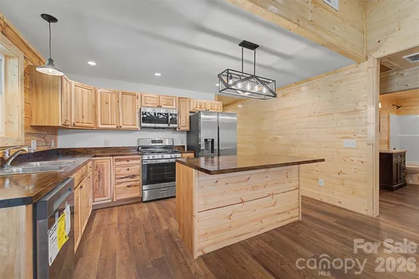 a kitchen with stainless steel appliances granite countertop a sink a stove and a wooden floors
