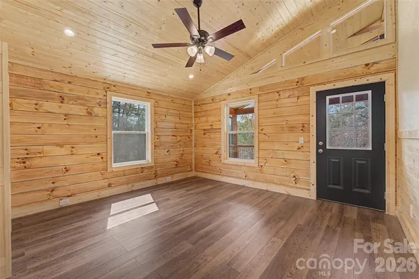 a view of an empty room with a window and wooden floor