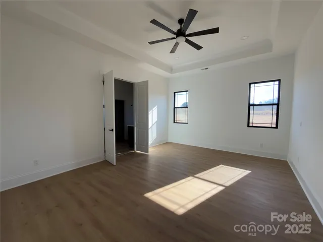 a view of an empty room with window and wooden floor