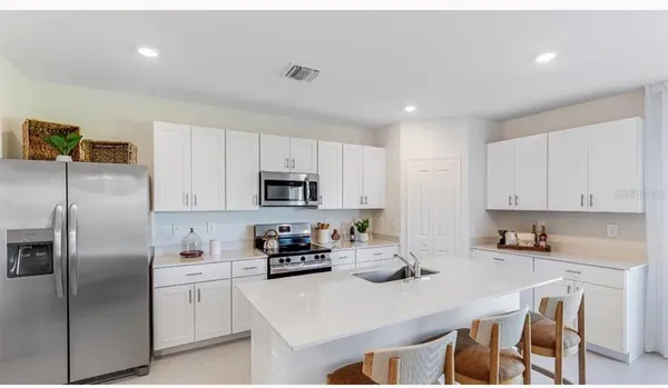 a kitchen with stainless steel appliances granite countertop a refrigerator a stove a sink a dining table and chairs