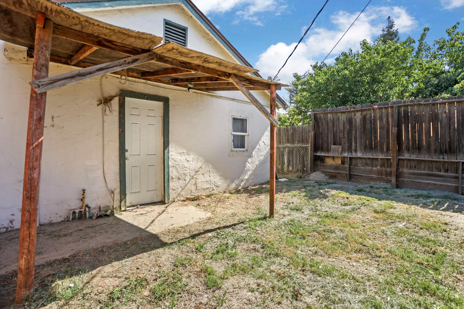 916 Elm Avenue Modesto, CA 95351 - Photo 52 of 52 Rear exterior view with private yard area, side entry, shade structure, and fencing repair/maintenance needed to covering and fencing.