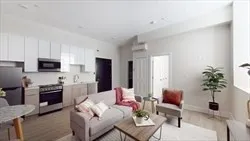 a living room with furniture potted plant and kitchen view