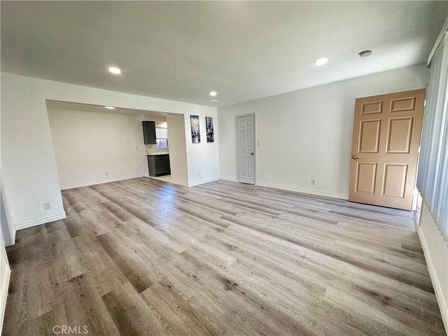 a view of empty room with wooden floor and window
