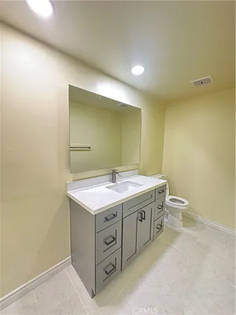 a bathroom with a granite countertop sink a toilet and a mirror