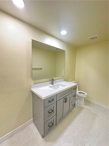a bathroom with a granite countertop sink a toilet and a mirror
