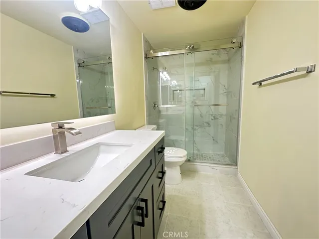 a bathroom with a sink a toilet a mirror and shower