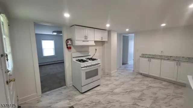 a kitchen with stainless steel appliances granite countertop a stove a sink and a refrigerator with white cabinets