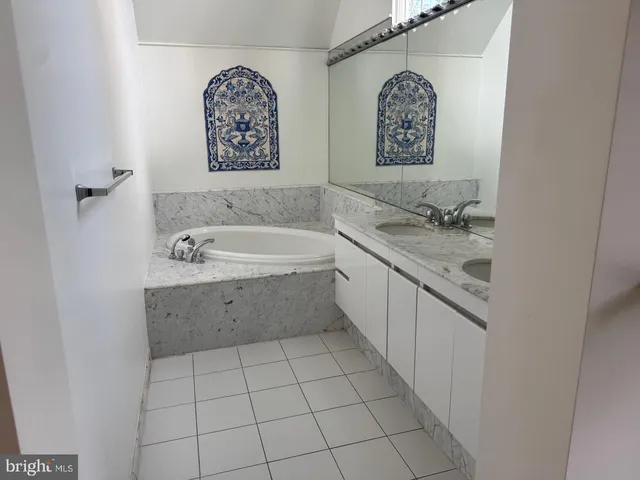 a bathroom with a tub sink and mirror