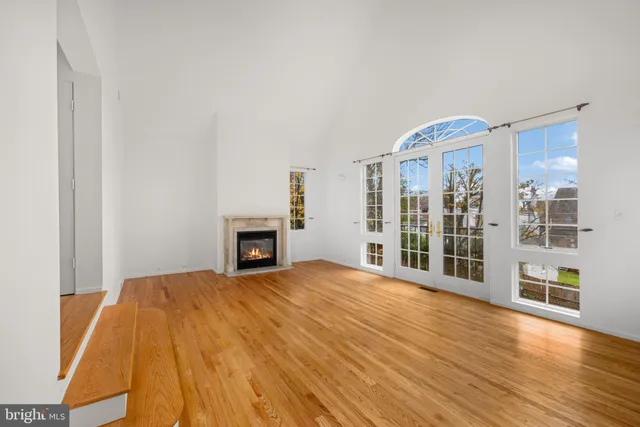 a view of an empty room with wooden floor and a fireplace