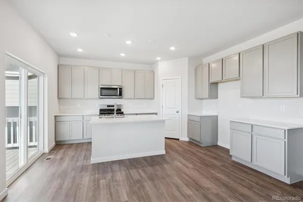 a kitchen with wooden floors white cabinets appliances and wooden floor